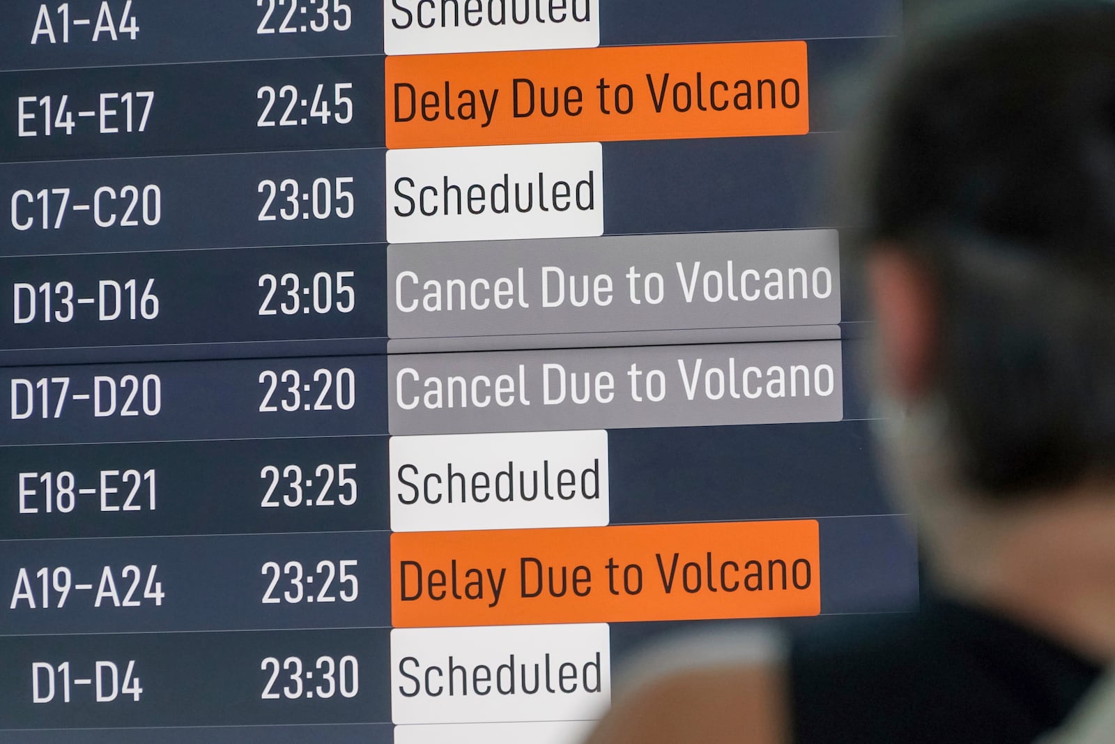 A passenger checks an information board showing disrupted flight schedule due to the eruption of Mount Lewotobi Laki-Laki, at Ngurah Rai International Airport in Badung, Bali, Indonesia, Wednesday, June 18, 2025. (AP Photo/Herdyanto)
