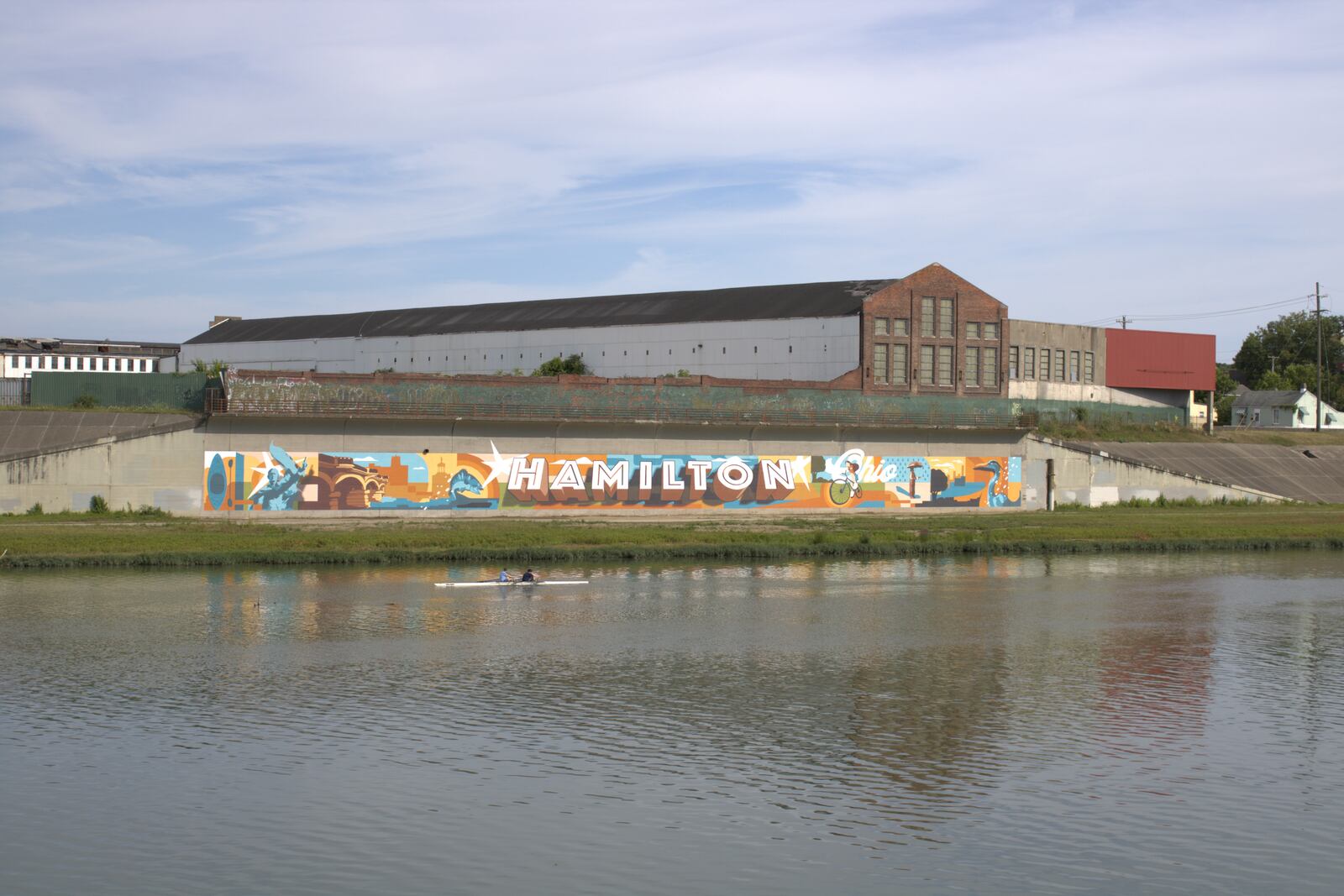 Rowers float down the Great Miami River past the new Hamilton mural on July 2.