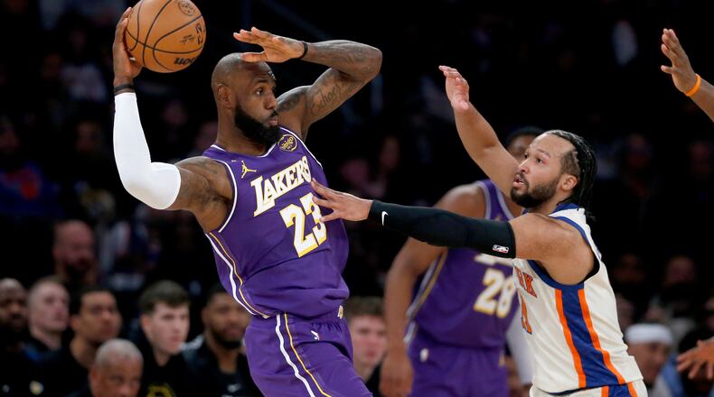 Los Angeles Lakers forward LeBron James, left, looks to pass the ball around New York Knicks guard Jalen Brunson, front right, during the first half of an NBA basketball game, Sunday, Feb. 1, 2026, in New York. (AP Photo/John Munson)