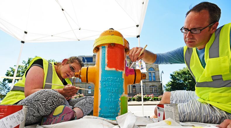 Last year, Morgan Gattermeyer, left, and Stephen Smith with Inside Out Studio painted a fire hydrant along High Street. The city of Hamilton has partnered with the YMCA and InsideOut Studio to paint about 275 fire hydrants throughout the city in either safety yellow or a creative design. NICK GRAHAM/STAFF