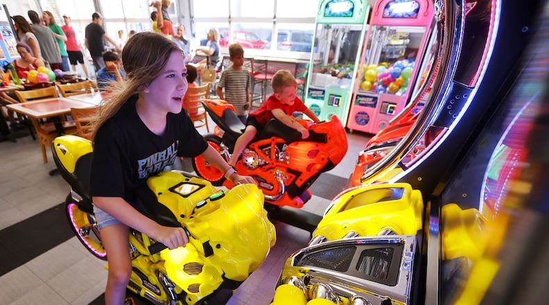 Jasmine Watkins, 11 and Dominic Watkins ride on a motorcycle game inside the new expansion at Pinball Garage in Hamilton. Pinball will be adding game machines to Spooky Nook Sports at Champion Mill in a new arcade there. FILE
