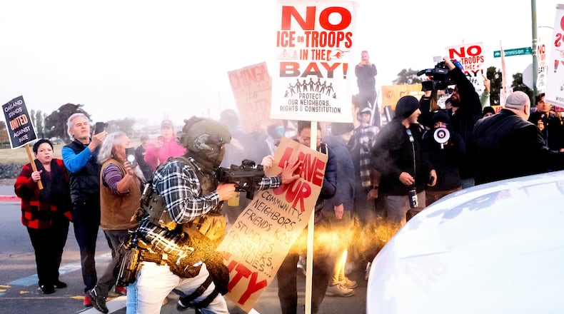 A person pushes a protester blocking a caravan of U.S. Customs and Border Protection personnel trying to enter Coast Guard Base Alameda on Thursday, Oct. 23, 2025, in Oakland, Calif. (AP Photo/Noah Berger)