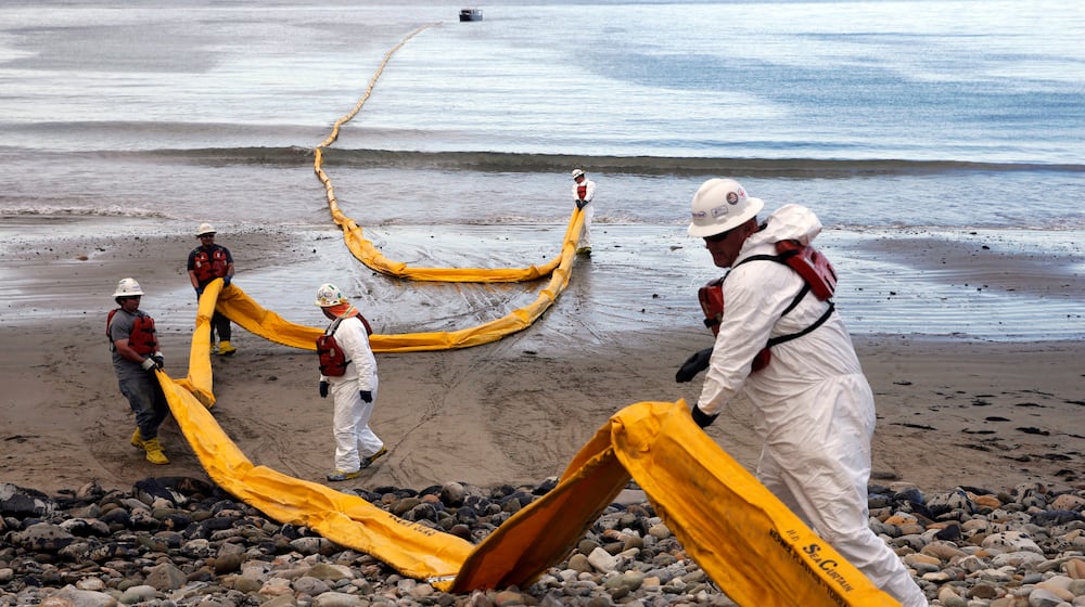 FILE - Workers prepare an oil containment boom at Refugio State Beach, north of Goleta, Calif., on May 21, 2015, two days after an oil pipeline ruptured, polluting beaches and killing hundreds of birds and marine mammals. (AP Photo/Jae C. Hong, File)