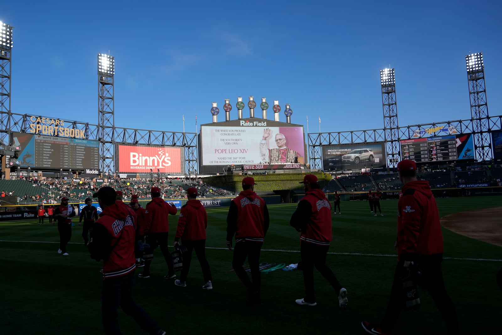 Chicago White Sox players walk on the field as the scoreboard honors Pope Leo XIV before a baseball game against the Miami Marlins Friday, May 8, 2025, in Chicago. (AP Photo/David Banks)