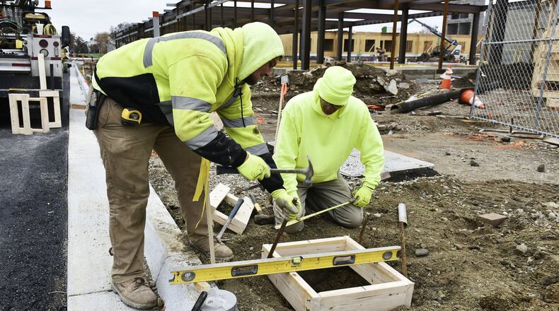 Jordon Preedom, left, and Jon Hetrick, with Bansal Construction, install forms for a lighting install along the Riverfront Plaza as construction continues on The Marcum retail and living space Nov. 13 in Hamilton. Tano Bistro will open a location in The Marcum next year. NICK GRAHAM/STAFF
