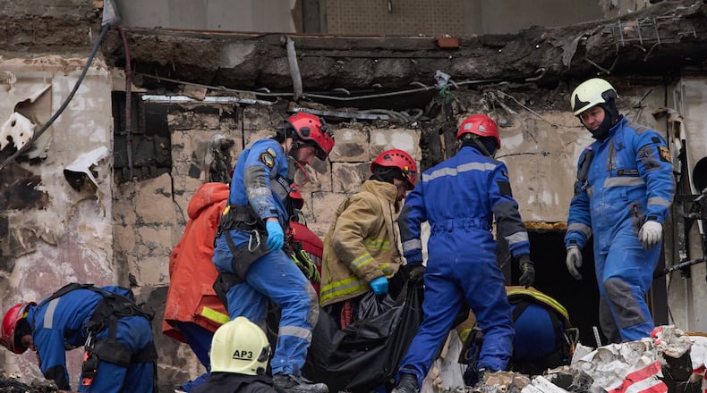 Rescuers carry the body of a victim after Russian drone hit a multi-storey apartment building during a massive missile and drone attack in Kyiv, Ukraine, Saturday, Dec. 27, 2025. (AP Photo/Efrem Lukatsky)