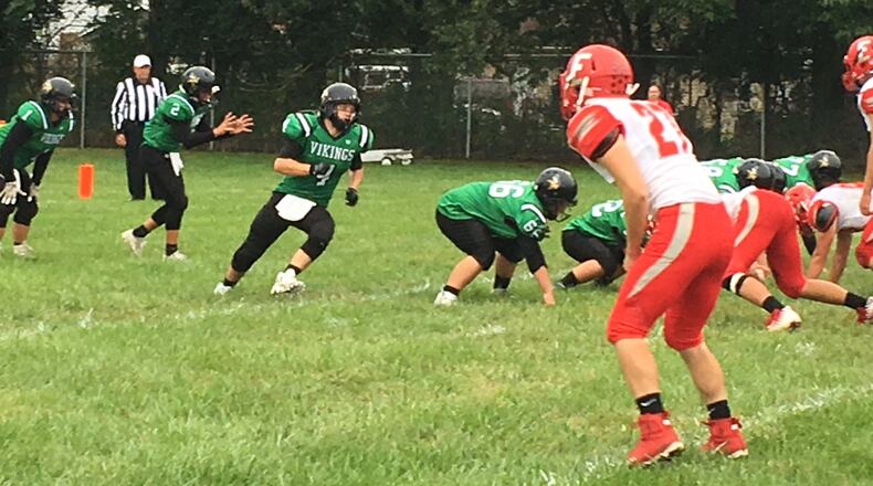 New Miami quarterback Trey Robinette prepares for the snap with Dalton Garrett (1) in the backfield and Brody Honaker (4) going in motion during a 54-6 loss to Marion Elgin at Mara Field in New Miami on Sept. 2. RICK CASSANO/STAFF