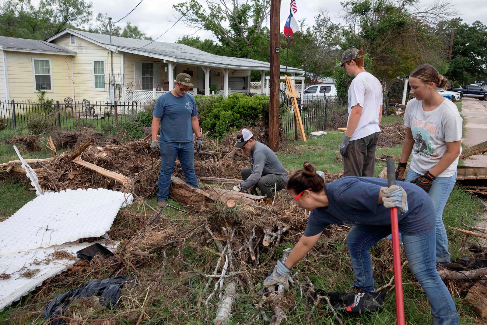 Volunteers from Kerrville Bible Church saw and haul tree debris in front of a flood-damaged home on Guadalupe Street in Kerrville, Texas, on Saturday, July 12, 2025. (AP Photo/Gabriela Aoun Angueira)