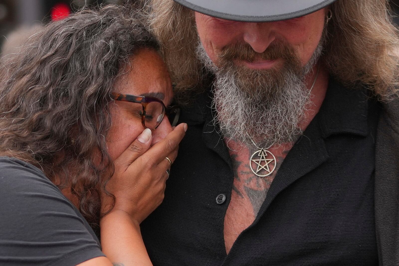 Music fans react after they lay flowers to commemorate the death of Ozzy Osbourne at the Black Sabbath Bridge in Birmingham, Wednesday, July 23, 2025. (AP Photo/Kin Cheung)