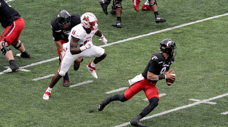 Cincinnati quarterback Desmond Ridder (9) is chased in the backfield by Miami (Ohio) defensive lineman Dominique Robinson (11) during the first half of an NCAA college football game Saturday, Sept. 4, 2021, in Cincinnati. (AP Photo/Jeff Dean)