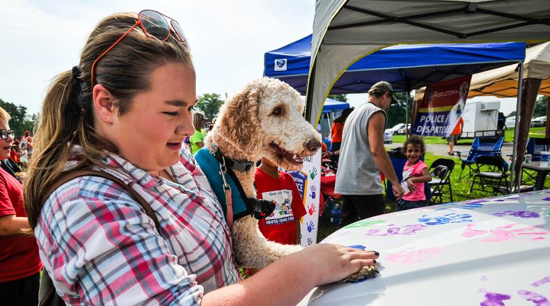 Emma McClung, 15, puts Sadie’s paw print on a Middletown Division of Police cruiser during Middletown’s National Night Out this past summer. Middletown City Council will soon give consideration for future improvements at Miami Park that include a new dog park.