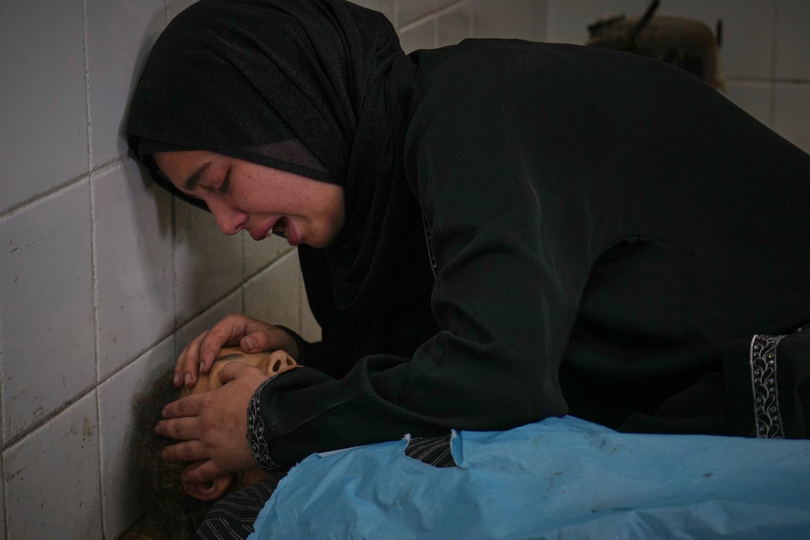 Sara Al-Nouri mourns over the body of her 13-year-old sister, Sama, who was among 10 people, including two women and five children, killed in an Israeli strike while they were waiting to receive nutritional supplements at a Project Hope-run medical clinic in Deir al-Balah, Gaza Strip, Thursday, July 10, 2025. (AP Photo/Abdel Kareem Hana)