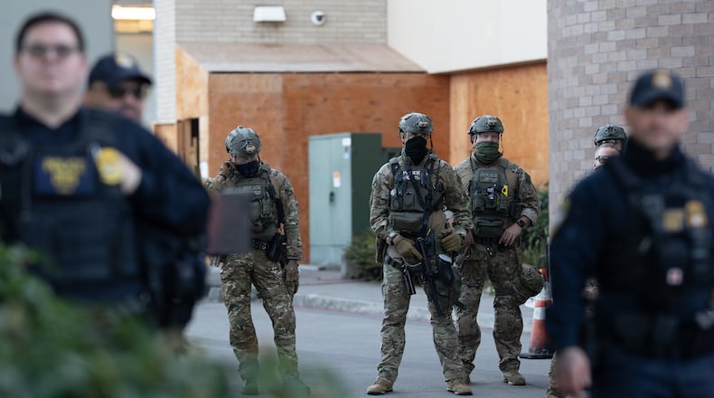 FILE - Law enforcement officers look out from a United States Immigration and Customs Enforcement (ICE) facility Oct. 21, 2025, in Portland, Ore. (AP Photo/Jenny Kane, File)