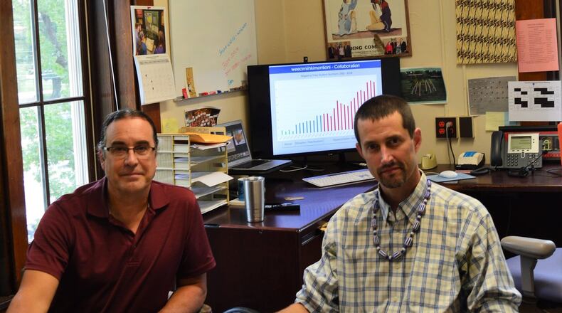 Daryl Baldwin, left, and George Ironstrack, of Miami University’s Myaamia Center, look at some of the tribe’s preserved records in the center’s office in Bonham House on the campus. CONTRIBUTED/BOB RATTERMAN