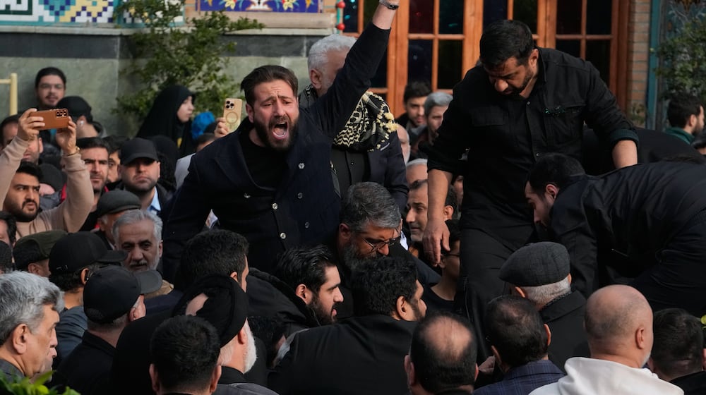 A man chants slogan while the body of Gen. Ali Shamkhani, secretary of Iran's Defense Council and a senior adviser to the Supreme Leader who was killed in a strike, is being buried at the courtyard of the Imamzadeh Saleh shrine in Tehran, Iran, Saturday, March 14, 2026. (AP Photo/Vahid Salemi)
