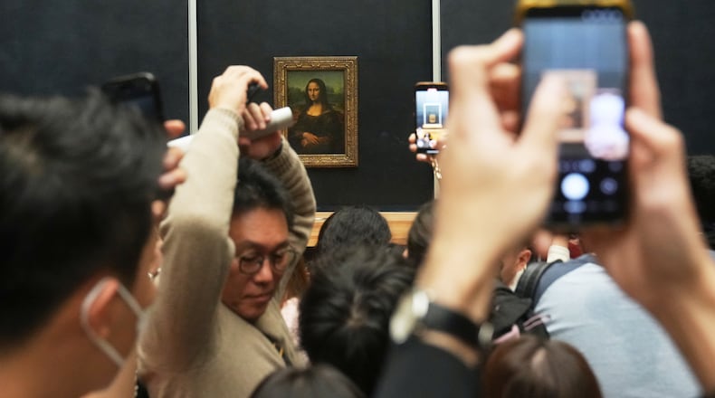 Visitors watch Leonardo da Vinci's painting Mona Lisa in Louvre museum three days after historic jewels were stolen in a daring daylight heist, Wednesday, Oct. 22, 2025 in Paris. (AP Photo/Thibault Camus)