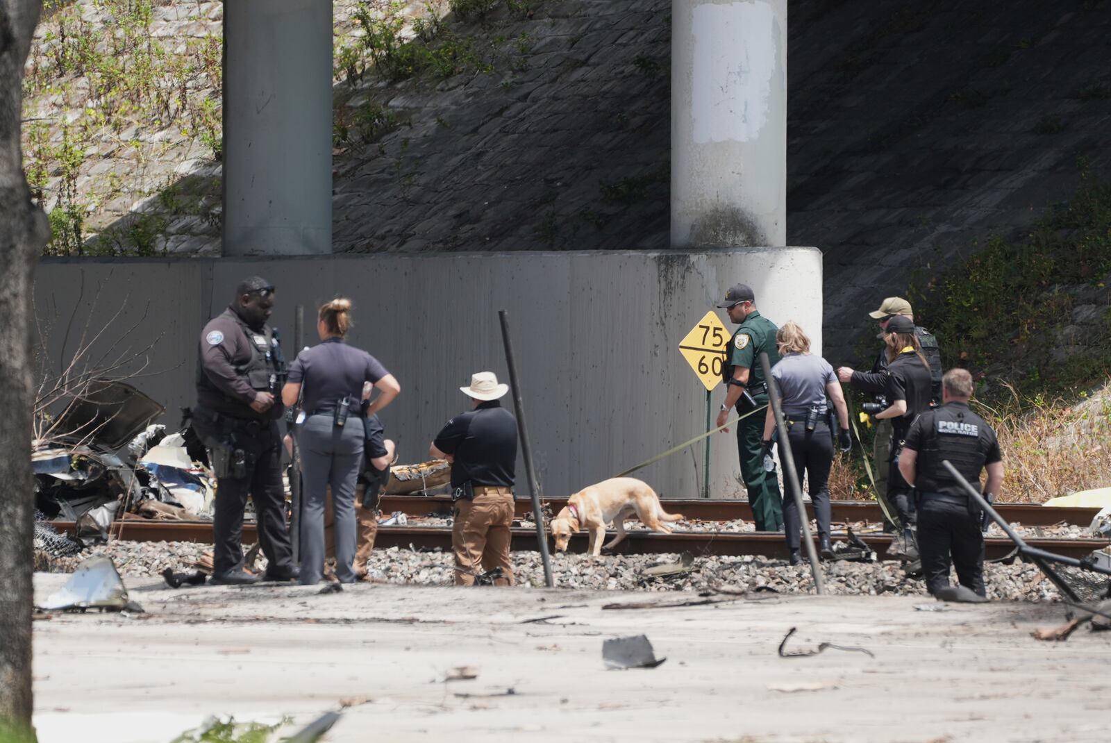 Emergency personnel respond to the area where a small plane crashed on the railroad tracks beneath the overpass near Interstate 95 in Boca Raton, Fla., on Friday, April 11, 2025. (AP Photo/Marta Lavandier)