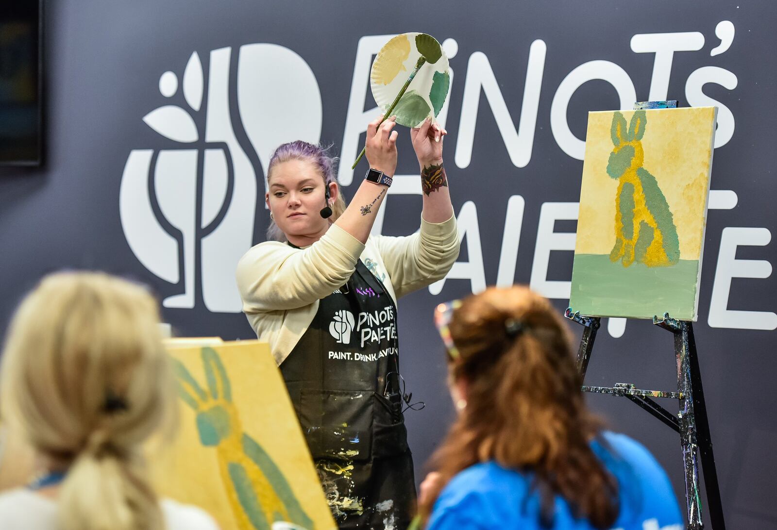 Missy Baker, assistant manager and artist at Pinot’s Palette, instructs visitors how to paint during an event at the Pinot’s Palette location on Tylers Corner in West Chester Township Monday, April 8, 2019. The business is a place to gather with friends with a glass of wine or beer while a local artist guides you through painting your own piece of art on a canvas. NICK GRAHAM/STAFF