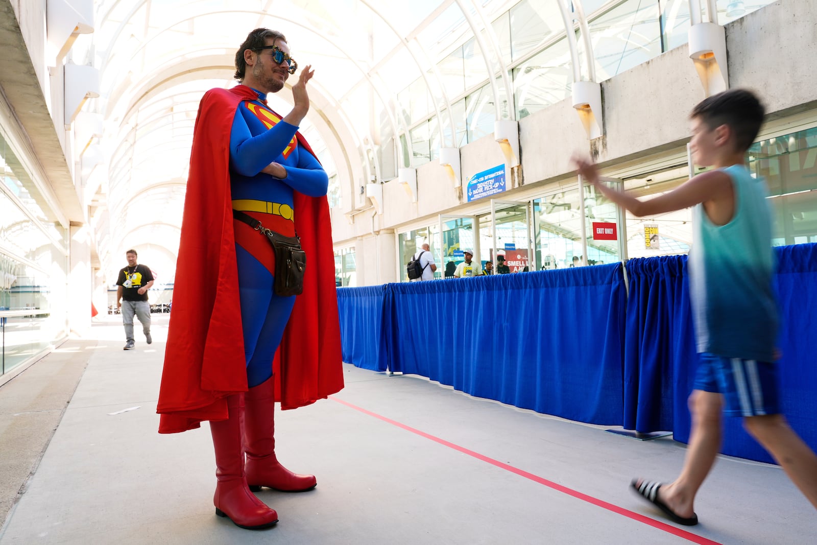 Comic-Con volunteer Chris Perry, left, dressed as Superman, waves to a young attendee before the 2025 Comic-Con International Preview Night on Wednesday, July 23, 2025, in San Diego. (AP Photo/Chris Pizzello)