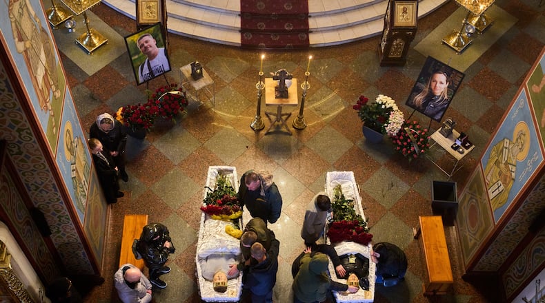 Relatives, colleagues and friends of two Ukrainian 43-year-old journalists Olena Hubanova, who worked under the pseudonym Alyona Gramova, and cameraman Yevhen Karmazin, who were killed on Thursday, Oct. 23, mourn over their coffins during a funeral service at St. Michael Monastery in Kyiv, Ukraine, Monday, Oct. 27, 2025. (AP Photo/Efrem Lukatsky)