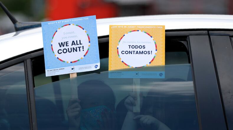 FILE - Two young children hold signs through the car window that make reference to the 2020 U.S. Census as they wait in the car with their family at an outreach event in Dallas, June 25, 2020. (AP Photo/Tony Gutierrez, File)