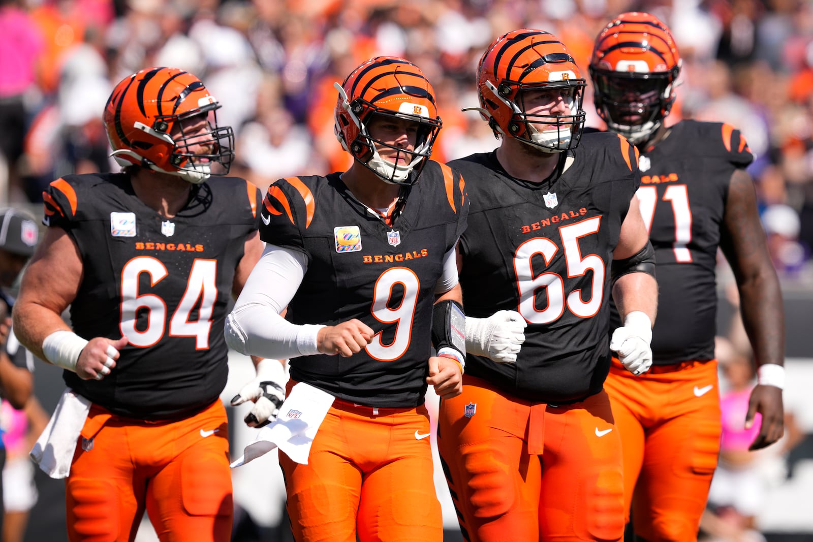 Cincinnati Bengals quarterback Joe Burrow (9) leaves the field with center Ted Karras (64), guard Alex Cappa (65) and offensive tackle Amarius Mims (71) after a series against the Baltimore Ravens during the first half of an NFL football game, Sunday, Oct. 6, 2024, in Cincinnati. (AP Photo/Jeff Dean)