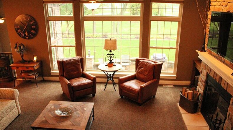 In the great room, earth-toned stone blocks in various shapes create the fireplace facing. Tall windows with transoms provide a plenty of natural light and a nature view.