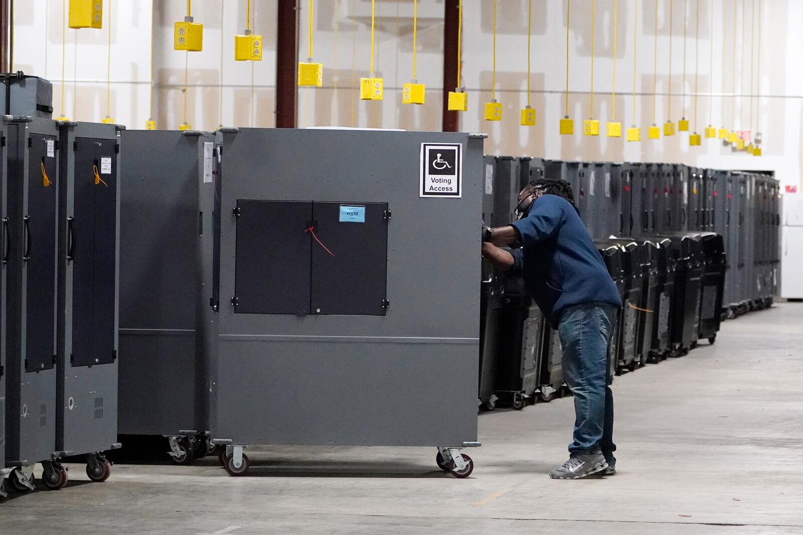 FILE - A worker returns voting machines to storage at the Fulton County Election preparation Center Nov. 4, 2020, in Atlanta. (AP Photo/John Bazemore)