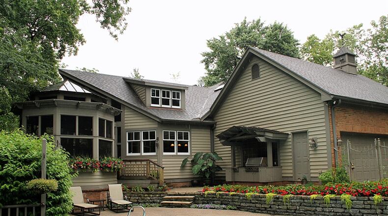 A screen-enclosed porch divides the back of the house. One side has an in-ground swimming pool surrounded by a paver-brick patio. The other side has a semi-covered paver patio with pathways to the spring-fed pond and waterfalls.