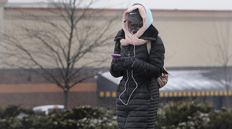 A woman bundles up against the cold as she walks along Old Troy Pike in Huber Heights, Monday, Jan. 25, 2021. A Winter Weather Advisory has been issued as freezing rain and a wintry mix move into the area. MARSHALL GORBY\STAFF