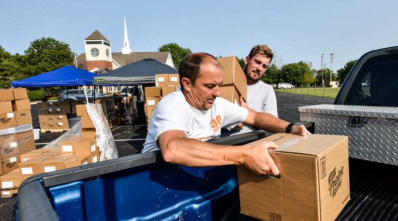 Clint Miracle, left, and Joshua Smalley, volunteers at Lakota Hills Baptist Church on Tylersville Road in West Chester Township, load up boxes of food for the Farmers to Families food program Tuesday, Sept. 15, 2020. NICK GRAHAM / STAFF