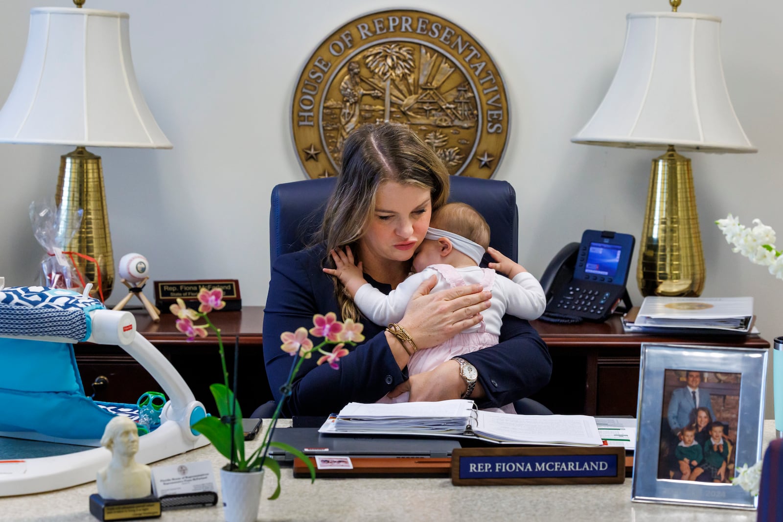 Florida Rep. Fiona McFarland, R-Sarasota, holds her 7-month-old daughter Grace Melton while working at her desk, Thursday, April 17, 2025, in Tallahassee, Fla. (AP Photo/Colin Hackley)