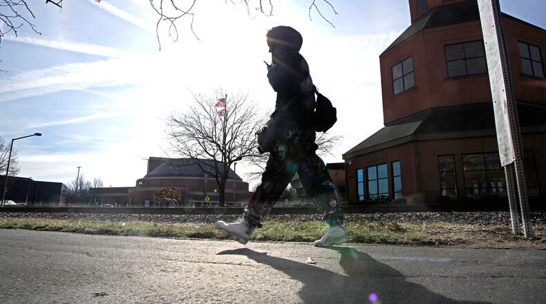 A woman walks in the sunshine Thursday, Feb. 1, 2024 as she makes her way along the Simon Kenton Trail in downtown Springfield. BILL LACKEY/STAFF