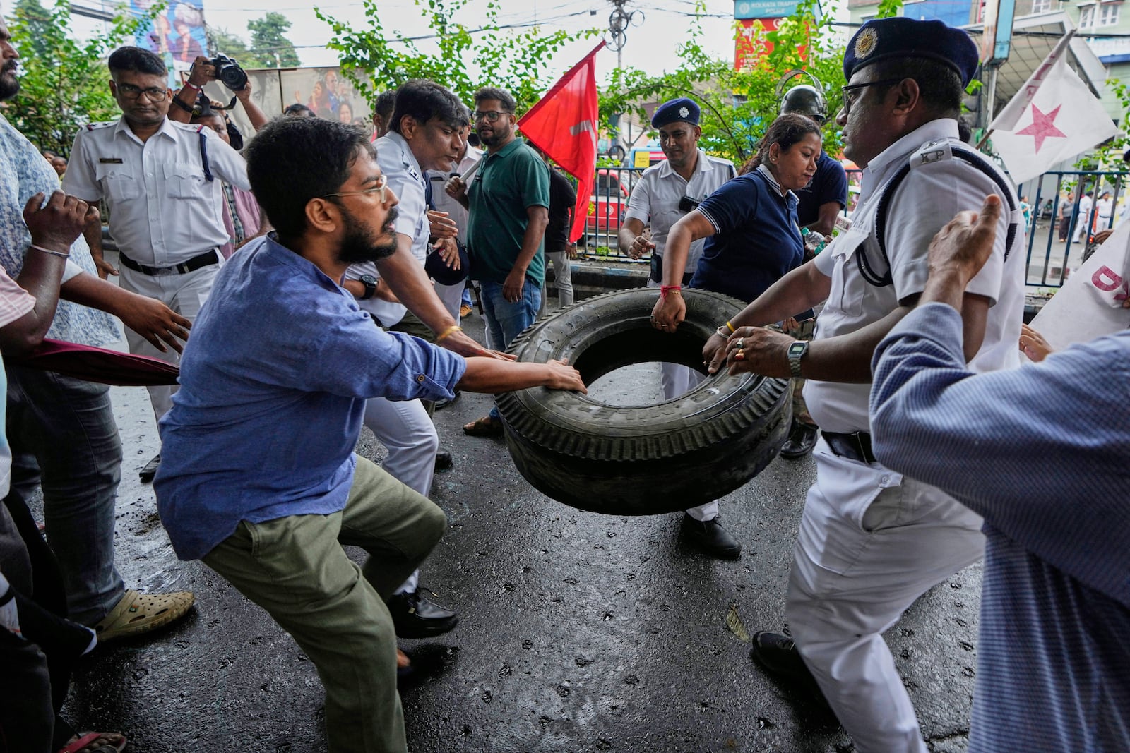 Policemen snatch a car tire that was used to make a road block from a supporter of Centre of India Trade Unions, CITU, during a nation-wide strike to protest what they call the anti-labor and anti-poor policies of the federal government, in Kolkata, India, Wednesday, July 9, 2025. (AP Photo/Bikas Das)