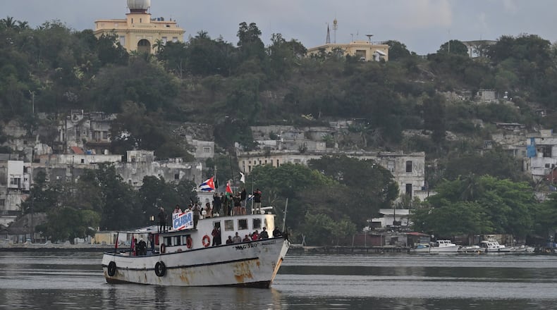 Activists wave Cuban and Palestinian flags from the vessel Maguro, arriving from Mexico with humanitarian aid as part of the "Nuestra America," or Our America convoy, in Havana Bay, Cuba, Tuesday, March 24, 2026. (AP Photo/Jorge Luis Banos)