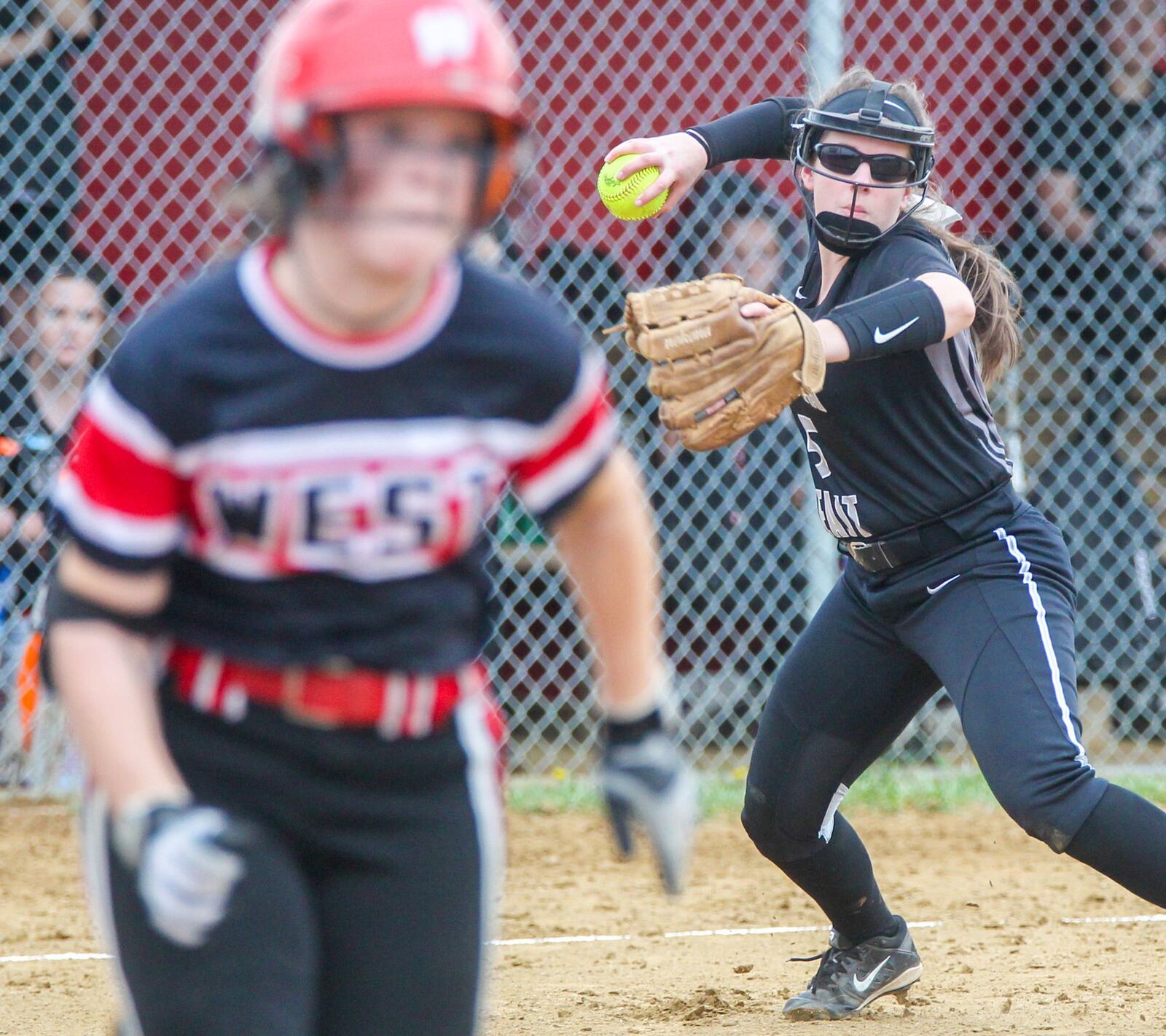 Lakota East third baseman Brianna Castner (5) throws out a Lakota West runner at first during their game at West on Tuesday. GREG LYNCH/STAFF