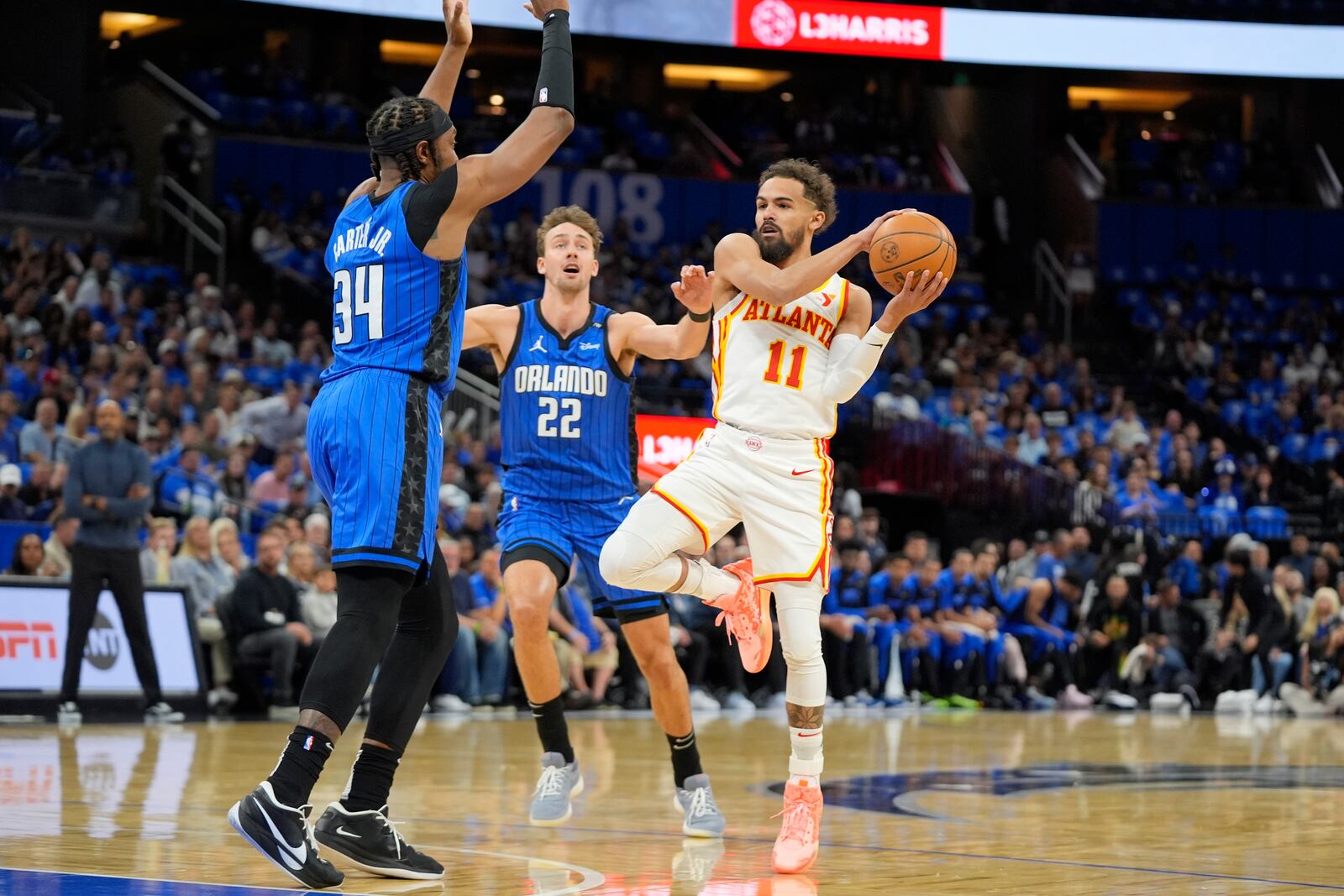 Atlanta Hawks guard Trae Young (11) looks to pass the ball as Orlando Magic center Wendell Carter Jr. (34) and forward Franz Wagner (22) defend during the first half of an NBA play-in tournament basketball game, Tuesday, April 15, 2025, in Orlando, Fla. (AP Photo/John Raoux)