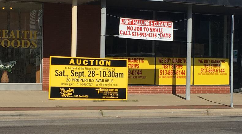 Auction signs like this were up this summer on properties offered in the estate auction of a Hamilton dermatologist. The buyers of one of those buildings now under contract plan to create a restaurant. MIKE RUTLEDGE/STAFF