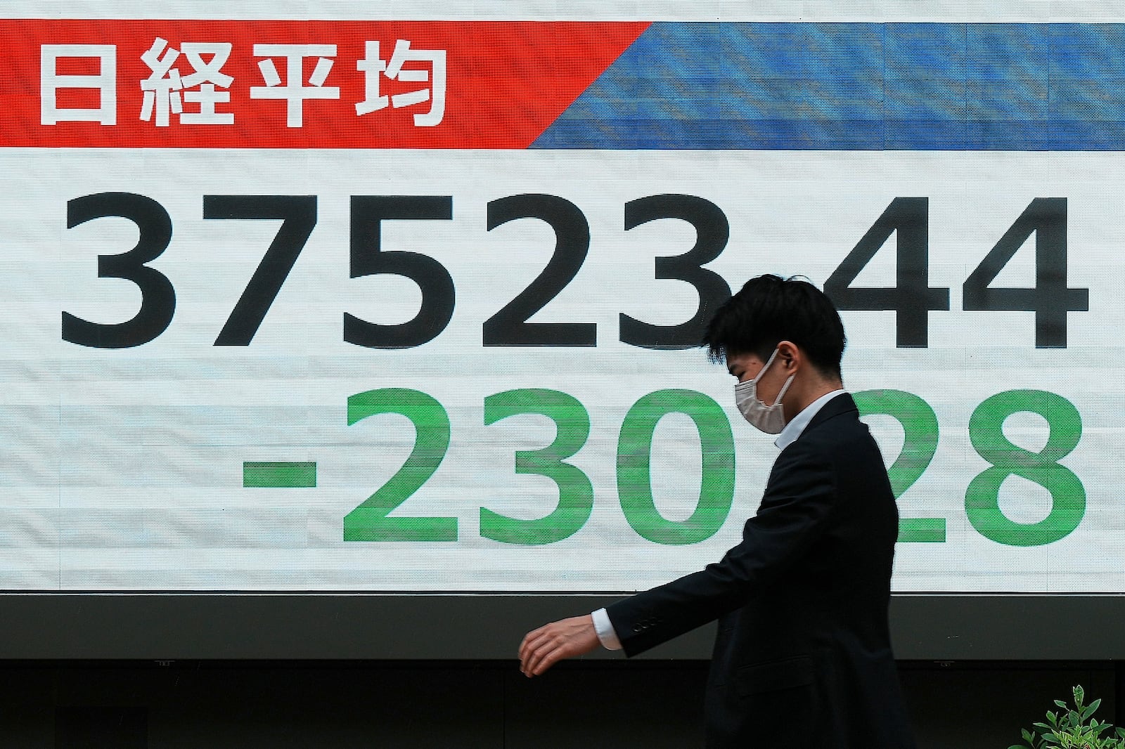 A person walks in front of an electronic stock board showing Japan's Nikkei index at a securities firm Monday, May 19, 2025, in Tokyo. (AP Photo/Eugene Hoshiko)