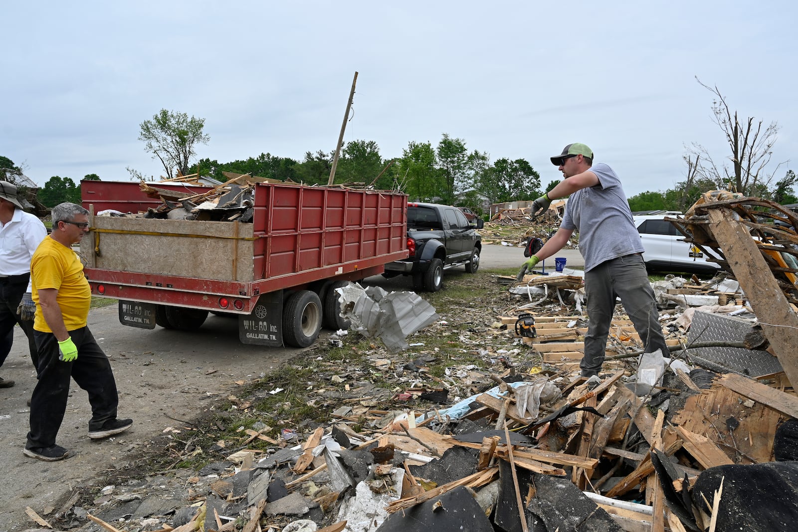 Volunteers load a dump truck with debris during cleanup efforts after severe storms in the Sunshine Hills neighborhood in London, Ky., Monday, May 19, 2025. (AP Photo/Timothy D. Easley)
