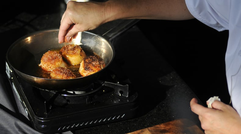 Executive Chef Michelle Brown of Jag's Steak & Seafood in West Chester Twp. performs a cooking demonstration on Tuesday, Aug. 18, 2015, at the Lindner Family Tennis Center during the Western & Southern Open in Mason, Ohio. She prepared caramelized chimichurri diver scallop over citrus arugula salad. (MICHAEL D. PITMAN/STAFF)