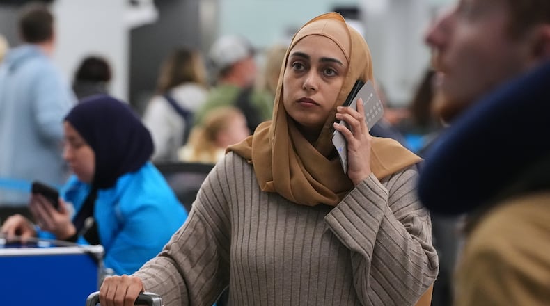 A traveler checks the status of her flight at the O'Hare International Airport in Chicago, Sunday, Nov. 30, 2025. (AP Photo/Nam Y. Huh)