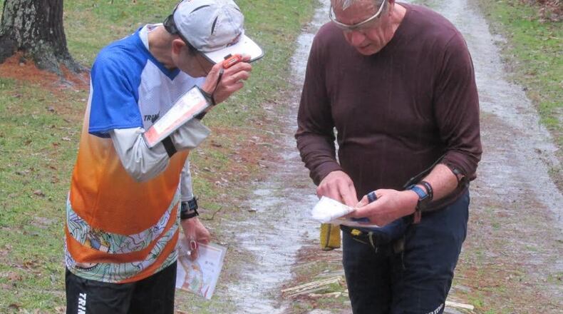 Shin Shimizu, of Columbus and Bruce Moore, of Louisville, Ky. compare maps and routes after finishing on a very wet day.  REX SETTLEMOIR/CONTRIBUTED