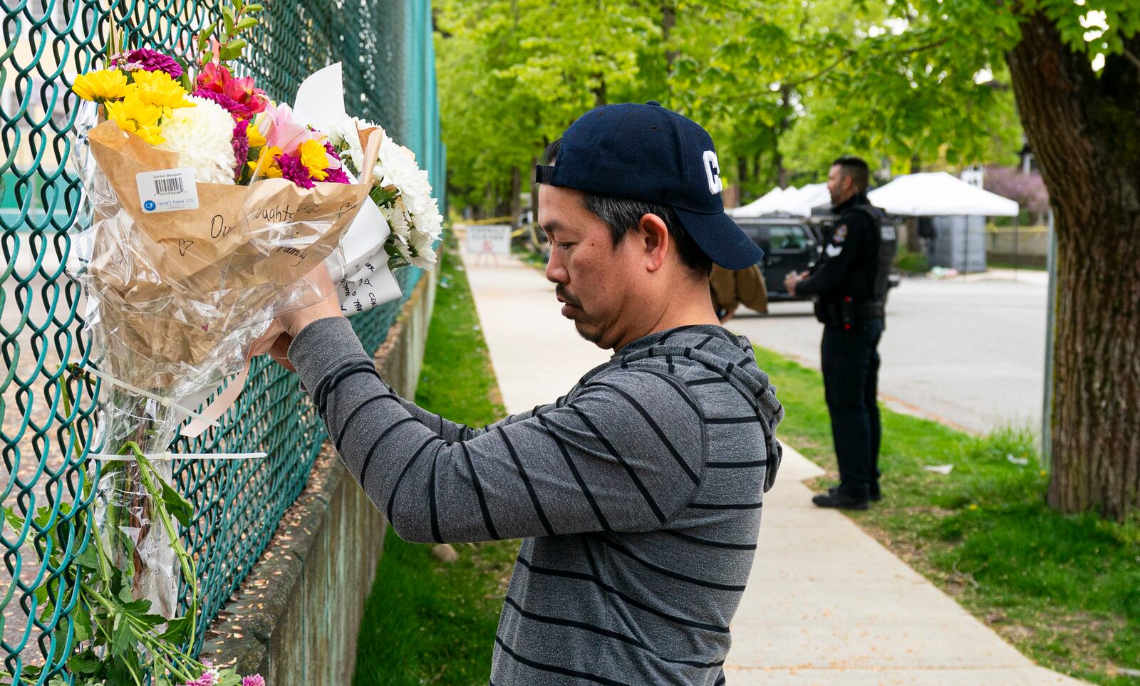 A man leaves flowers on a fence, near the location where a vehicle drove into crowd at a street festival last night, in Vancouver, British Columbia, Sunday April 27, 2025. (Rich Lam/The Canadian Press via AP)