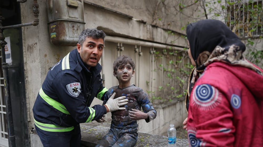 A first responder assists an injured boy following a strike that hit a residential building amid the U.S.-Israeli military campaign in Tehran, Iran, Saturday, March 28, 2026. (AP Photo/Sajad Safari)