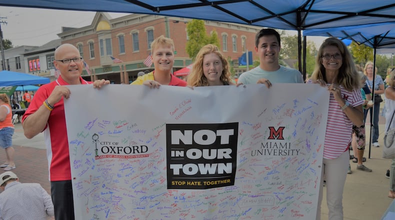 Holding up the banner people had signed in support of the Not In Our Town pledge are (from left) Miami President Gregory Crawford, Sean Perme, Cecilia Comerford. Michael Zeh and Renate Crawford. CONTRIBUTED/BOB RATTERMAN