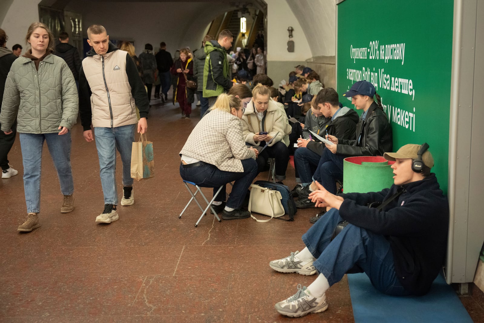 Schoolchildren do their homework and people hide in an underground metro station following air raid sirens alerting of a Russian missile attack in Kyiv, Ukraine, Wednesday, April 16, 2025. (AP Photo/Efrem Lukatsky)