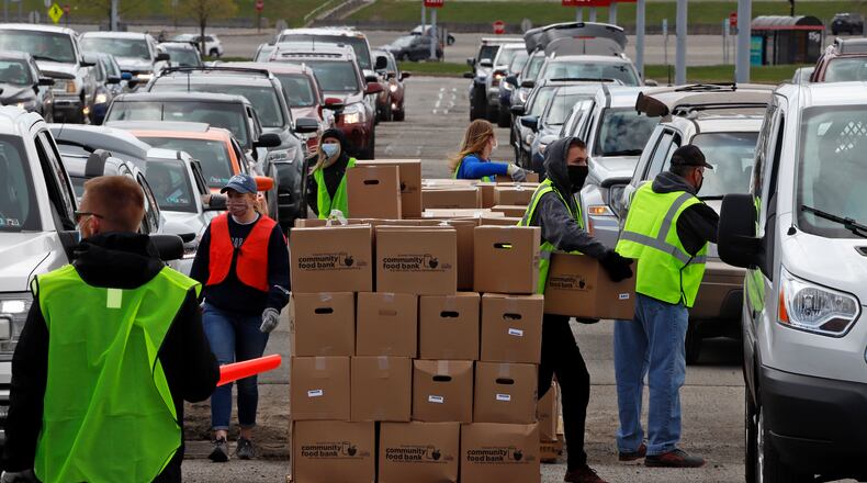 Using part of the Pittsburgh International Airport parking lot that has been left vacant by the COVID-19 pandemic, volunteers from the Greater Pittsburgh Community Food Bank load boxes of food into cars during a drive-up food distribution Wednesday. (AP Photo/Gene J. Puskar)