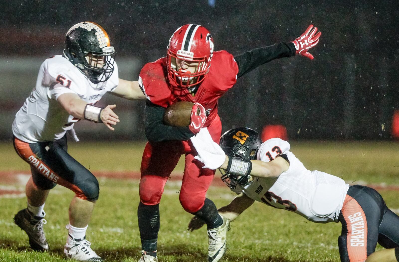 Madison’s Cameron Svarda (26) looks for yardage between Waynesville’s Mason Lukens (51) and Jaymes Bowman (13) during Friday night’s game at Brandenburg Field in Madison Township. NICK GRAHAM/STAFF