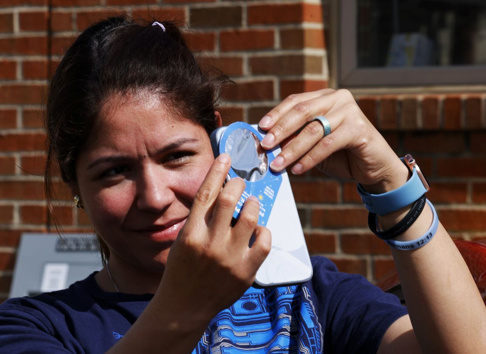 Kihelyn Castro tries out her solar filter in Hamilton Monday morning, April 8, 2024 before the total solar eclipse. NICK GRAHAM/STAFF